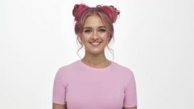 Neşeli genç bir kadın barış jesti yaparken beyaz arka planda izole edilmiş göz kırpıyor.