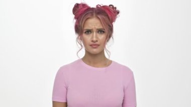 Şok olmuş genç bir kadın, beyaz arka planda elleri havada afallamış bir şekilde dikiliyor.