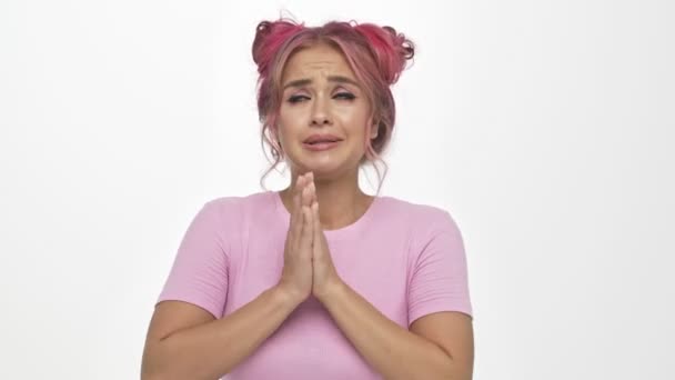 一位漂亮的年轻女子 有着一头粉色的发式 她一边祈祷 一边把双手分开在白色的背景下 — 图库视频影像