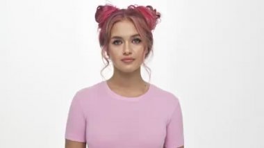 Renkli, pembe saçlı genç bir kadın beyaz arka planda izole bir şekilde kameraya hava öpücüğü gönderiyor.