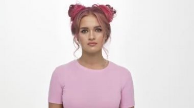 Renkli pembe saç stiline sahip hoşnutsuz genç bir kadın beyaz arka planda izole edilmiş bir baş parmak hareketi gösteriyor.