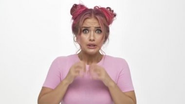 Pembe saçlı güzel bir kadın beyaz arka planda izole edilmiş bir şeyden korkmaya başlıyor.