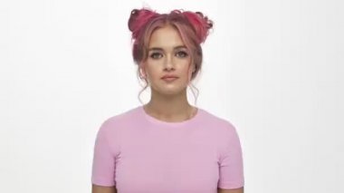 Pembe saçlı, yorgun bir genç kadın beyaz arka planda öldürücü bir jest yapıyor.