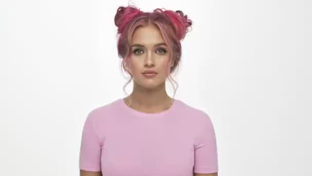 一位严肃的 一头粉色头发的年轻女子正在做着一个沉默的动作 这个动作与白色的背景格格不入 — 图库视频影像