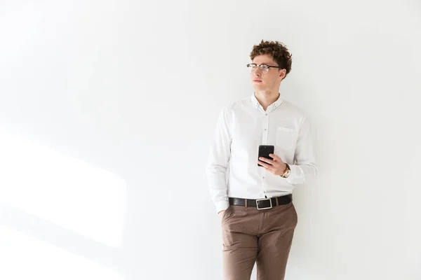 一个成功的年轻迷人的卷发商人的画像 他站在白色背景的前面 用手机 — 图库照片