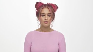 Renkli pembe saç stiline sahip hoşnutsuz genç bir kadın gözlerini beyaz arka planda soyutlamış.