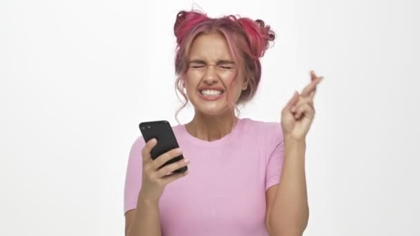白い背景にスマホを持ちながら交差点の指で立っているピンク色の髪型の美しい若い女性 — ストック動画