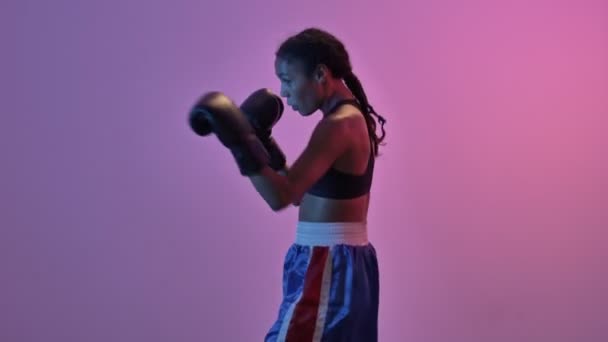 集中的非洲运动女拳击手在拳击手套训练中的侧视图 同时将目光从孤立的手电筒背景移开 — 图库视频影像