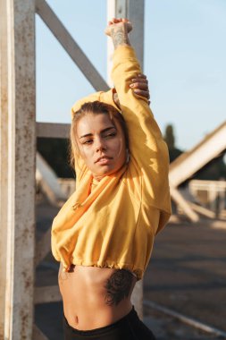 Genç ve güzel bir spor salonunun fotoğrafı. Açık havada esneme egzersizleri yapıyor..