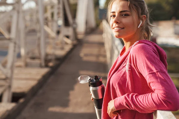 Aantrekkelijke Jonge Fitnessvrouw Die Buiten Brug Traint Naar Muziek Luistert — Stockfoto