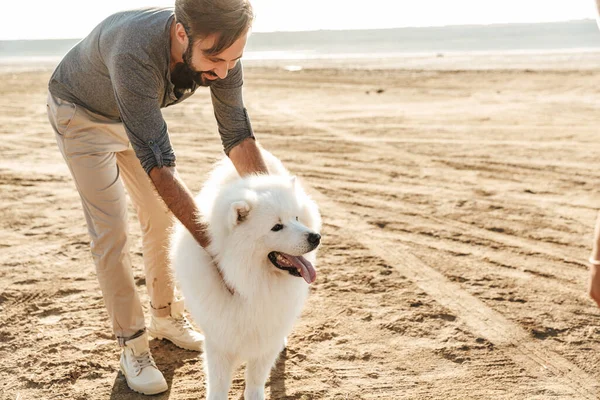 Vrolijke Jonge Man Spelen Met Zijn Hond Het Zonnige Strand — Stockfoto