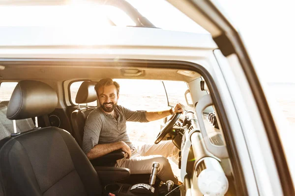 Beeld Van Knappe Positieve Jongeman Rijden Auto Buiten Het Strand — Stockfoto