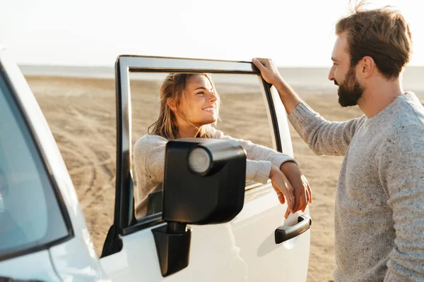 若い喜びの明るい楽観的な愛情のカップルの写真車の近くのビーチで屋外 — ストック写真