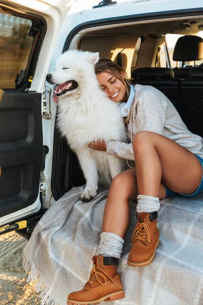 Afbeelding Van Glimlachende Optimistische Jonge Vrouw Knuffelen Hond Samoyed Buiten — Stockfoto