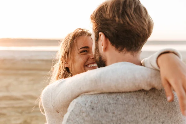 近视一对美丽的微笑的年轻夫妇站在阳光灿烂的海滩上 拥抱在一起 — 图库照片