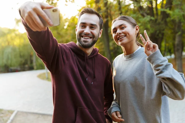 Zdjęcie Pięknej Szczęśliwej Pary Odzieży Sportowej Robiącej Selfie Komórce Gestykulującej — Zdjęcie stockowe