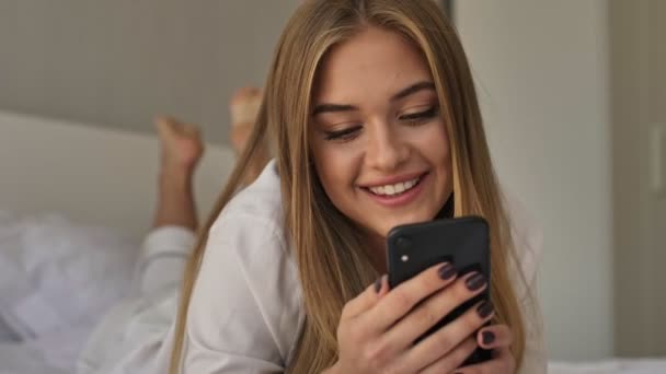 Une Jeune Fille Rieuse Pyjama Utilise Smartphone Tout Reposant Lit — Video