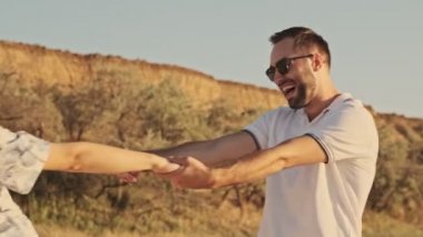 Neşeli ve çekici bir çift, güneşli plajda yürürken birlikte dönüyorlar.
