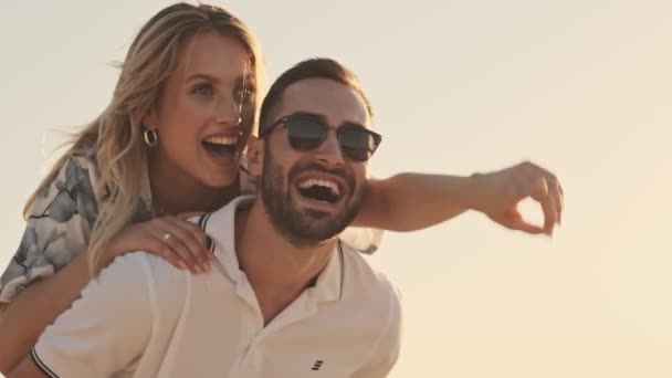 一对穿着休闲装的年轻貌美的夫妇在阳光明媚的海滩上玩得很开心 — 图库视频影像