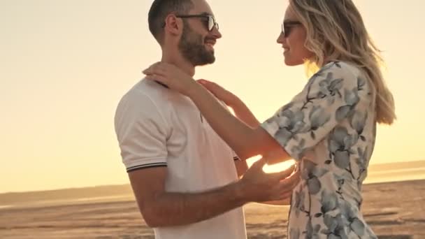 Joven Hombre Una Mujer Sonrientes Con Gafas Sol Abrazan Playa — Vídeo de stock