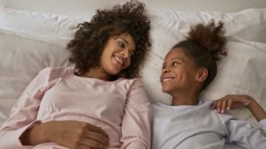 Neşeli Afrikalı bir kadının küçük güzel kızıyla evde yatarken eğlendiğinin en güzel görüntüsü.