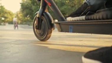 Genç bir adam spor alanında elektrikli scooter kullanıyor.