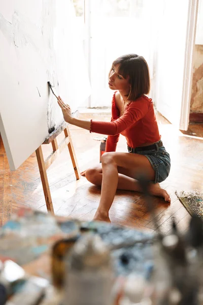 スタジオで絵を描きながら絵画ツールを使用した若い白人芸術家女性の肖像画 — ストック写真