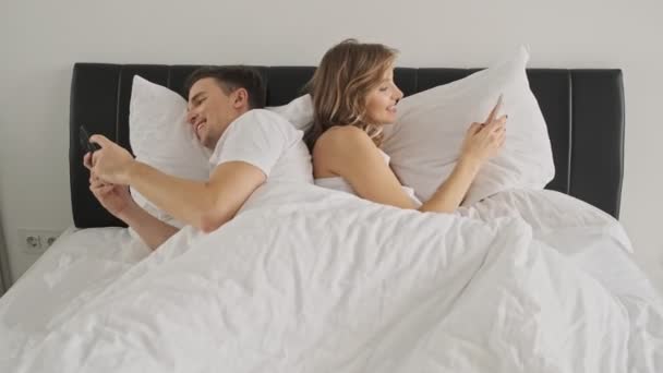 Una Feliz Pareja Sonriente Está Acostada Cama Espalda Con Espalda — Vídeo de stock