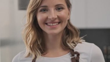 Cilveli genç bir sarışının yakın çekim görüntüsü kameraya içeride gülüyor.