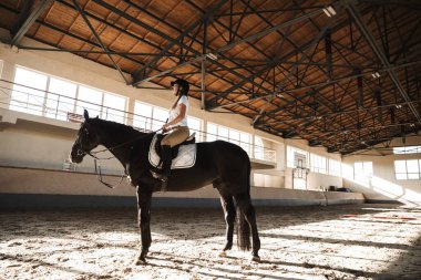 Kırsal kesimde eğitim alanında at şapkası takan hoş, genç, sarışın bir kadının fotoğrafı..