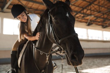 Antrenman alanında, kırsalda at şapkası takan genç, güzel, güzel bir kadının fotoğrafı..