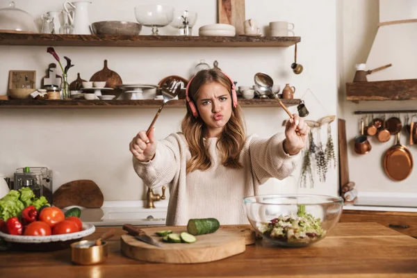 Mutfakta Yemek Pişirirken Kulaklık Takan Sıradan Giyinen Üzgün Bir Kadın — Stok fotoğraf