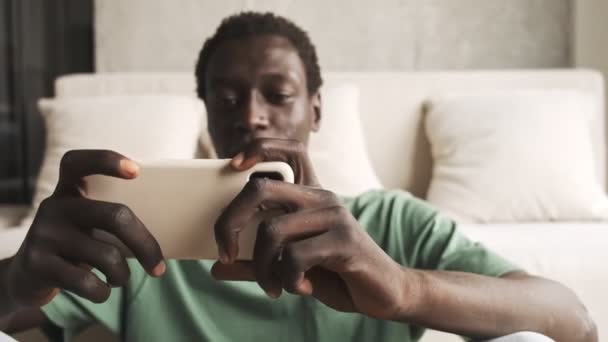 Ένας Ελκυστικός Αφροαμερικάνος Καθημερινά Ρούχα Χρησιμοποιεί Smartphone Του Ενώ Κρατάει — Αρχείο Βίντεο