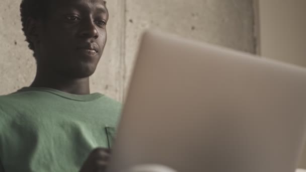 Крупным Планом Сфокусированный Вдумчивый Африканский Американец Смотрит Серебряный Ноутбук Гостиной — стоковое видео