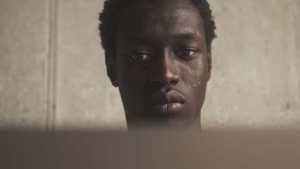 一位心平气和的非洲裔美国人坐在客厅里 正在用他的银色手提电脑近距离观察他的近景 — 图库视频影像