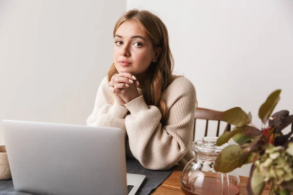 照片中年轻的高加索女人穿着休闲装 用笔记本电脑 在舒适的房间喝茶 — 图库照片