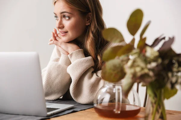 年轻迷人的女人穿着休闲装 在舒适的房间里用笔记本电脑喝茶的照片 — 图库照片