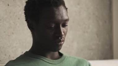 Sakin ve odaklanmış genç bir Afrikalı Amerikalının yakın plan görüntüsü oturma odasında oturan gümüş dizüstü bilgisayarı üzerinde çalışıyor.