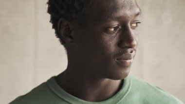 Pozitif gülüşlü, yakışıklı, Afro-Amerikan bir adamın yakın çekim görüntüsü açık oturma odasındaki kameraya doğru dönüyor.