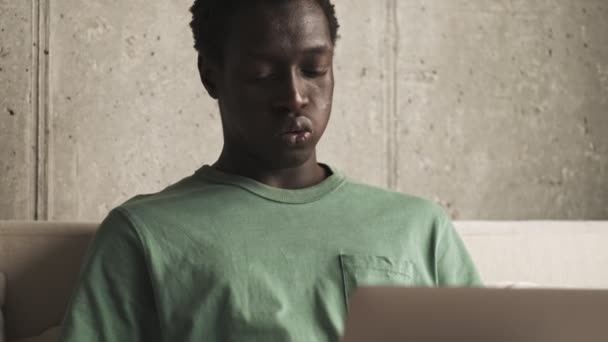 Niezadowolony Młody Afrykański Amerykanin Używa Swojego Srebrnego Laptopa Salonie — Wideo stockowe