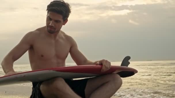 Ruhigen Bärtigen Schönen Mann Putzt Ihr Surfbrett Während Sie Strand — Stockvideo