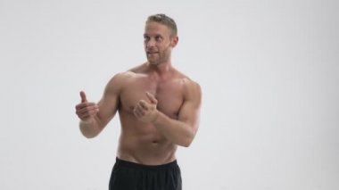 Yakışıklı, genç, yarı çıplak bir sporcu beyaz arka planda izole edilmiş basketbol topunu yakalıyor.