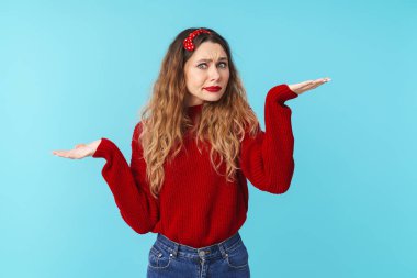 Kafası karışık, bantlı, yana bakan ve mavi arka plandan elini kaldıran güzel bir kadın görüntüsü.