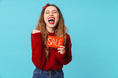 Pankart tutan heyecanlı sarışın bir kadın ve mavi arka planda izole edilmiş bir jest yapıyor.