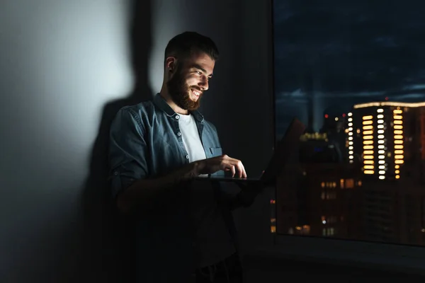 Jovem Sorridente Confiante Trabalhando Computador Portátil Enquanto Está Dentro Casa — Fotografia de Stock