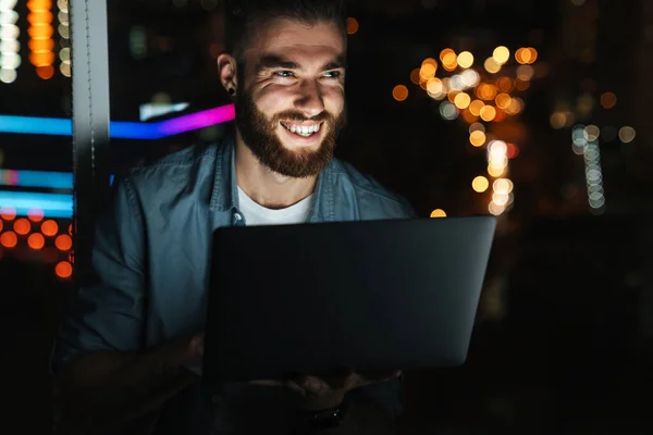 Šťastný Mladý Muž Pracující Notebooku Zatímco Stojí Noci Před Oknem — Stock fotografie