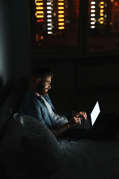 Sorridente Giovane Uomo Barbuto Sdraiato Sul Letto Casa Notte Lavorando — Foto Stock