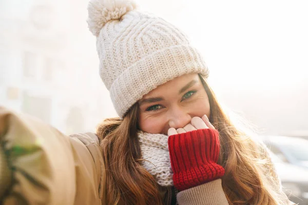 一个穿着冬衣 头戴一顶帽子站在城市街道上 自拍的漂亮姑娘的近照 — 图库照片