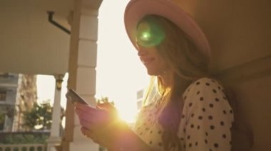 Pembe şapkalı genç bir kadın yazın dışarıda kolajların yanında yürürken sohbet ediyor.