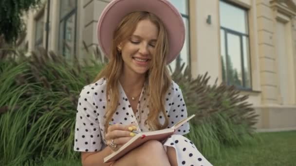 Uma Jovem Mulher Sorrindo Usando Chapéu Rosa Está Fazendo Anotações — Vídeo de Stock